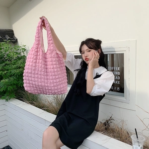 Detailed close-up of pink puff bubble textured shoulder bag on model in natural light