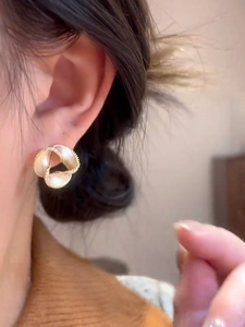 Detail view of 14K gold plated floral stud earring with crystals on a female model
