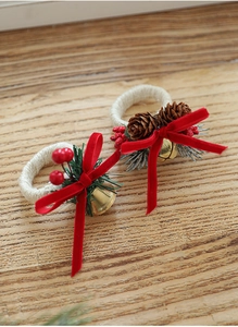 Close-up of rustic Christmas napkin rings with pine cones, red berries and gold bells