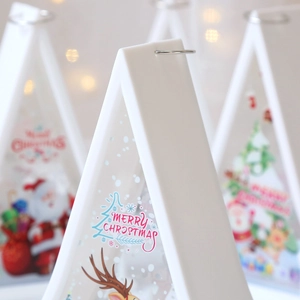 Macro detail of white Christmas lantern featuring Santa and reindeer with warm light