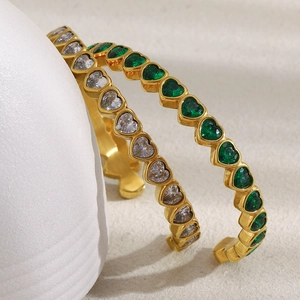 Dettaglio di bracciali placcati oro 18 carati a forma di cuore con zirconi bianchi e verdi
