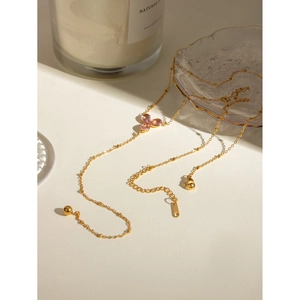 Detail of 18k gold plated necklace with a pink flower pendant and tassel drop