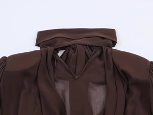 Dettaglio dello scollo a incrocio e della trama leggera sul vestito corto marrone scuro