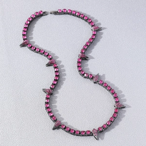 Hip hop black spiked necklace with pink crystals on grey textured background