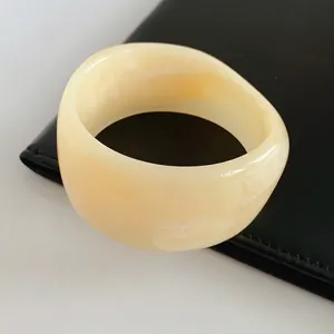 Minimalist wide resin bangle in cream white on a black leather surface