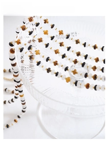 Detail of beaded necklace with white jade, tiger eye, black agate and gold metal spacers