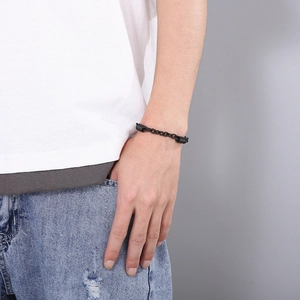 Close-up of a black chain bracelet with cylindrical metal fasteners on a model's wrist