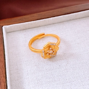Macro detail of 24K gold-plated flower ring with brushed metal texture and stone inlay