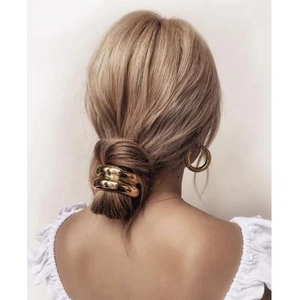 Dettaglio dell'elastico per capelli dorato ondulato e orecchini coordinati sul modello
