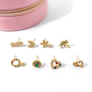 Detailed macro view of 8 gold stud earrings with colorful zircons on a pink jewelry box