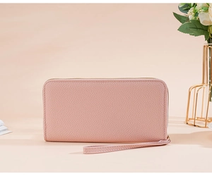 Pink lychee texture long wallet with wrist strap shown in professional still life photography