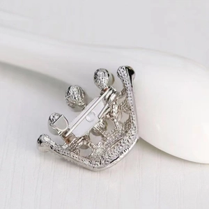 Macro view of the crown brooch back showing silver matte finish and secure pin mechanism