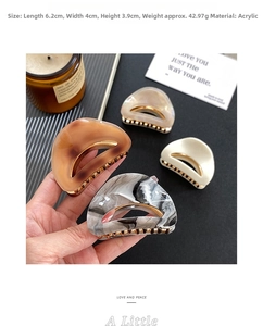 Detailed size view of four acrylic hair claws in amber and pearl white finishes
