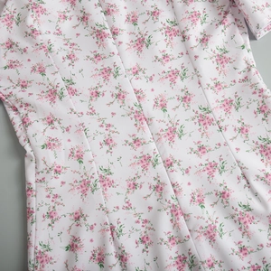 Dettaglio della stampa floreale rosa su abito bianco con cuciture in vita di pregio