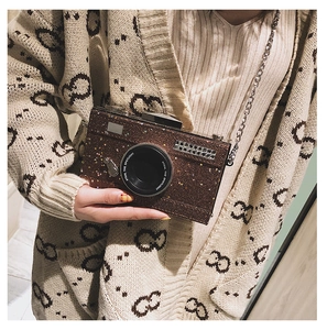 Detail of camera-shaped crossbody bag featuring glitter finish and silver chain strap