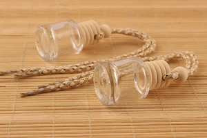 Detail of 8ml clear glass car perfume bottles with wooden caps on a bamboo mat