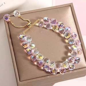 Detail of adjustable gold-tone crystal bead bracelet with iridescent faceted charms