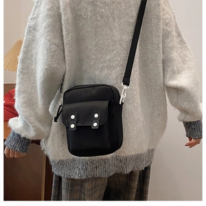 Detail of black canvas crossbody bag with silver round buttons and white hook clips