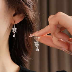 Gros plan de boucles d'oreilles argentées avec pendentifs papillon en zircone sur modèle