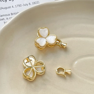 Macro detail of gold-plated clover jewelry clasps with white mother-of-pearl inlay