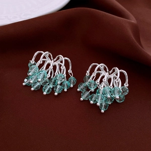 Detailed shot of silver tassel earrings with teal faceted beads on vintage brown fabric