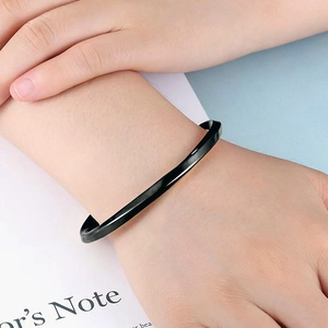 Detail of a matte black twisted Mobius bracelet on wrist with a modern minimalist style