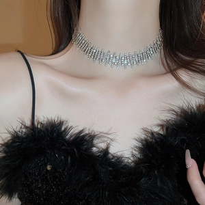 Macro shot of silver rhinestone choker necklace on a model wearing black feathers