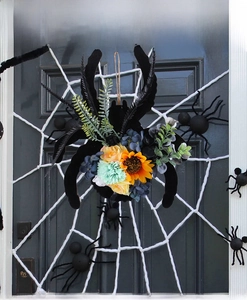 Détail d'une couronne d'araignée d'Halloween avec tournesols et succulentes sur porte en bois