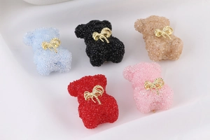 Detailed view of colorful grainy texture bear charms with golden bowties for DIY crafts