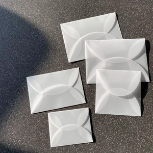 Cinque buste in carta velina traslucida con chiusura a petalo su sfondo grigio