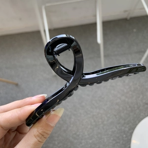 Detailed close-up of large black high-gloss hair claw clip showing durable cross-spring structure
