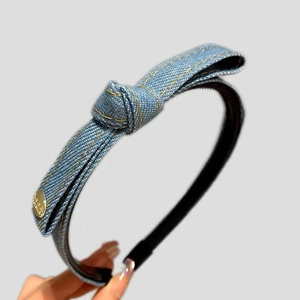 Blue denim knotted headband with chic gold emblem and stitching details for women