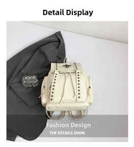 Detail of cream backpack showing metal insect buckle and silver rivets on textured faux leather