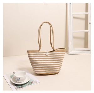 Detail of beige striped woven tote bag with a white pearl decorative buckle on it