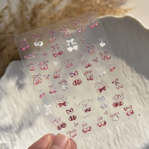 Macro detail of cherry and bow nail stickers with glitter laser effects on model ta-385