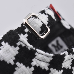 Detail of black and white houndstooth fabric with metal adjustment buckle on baseball cap