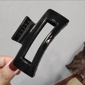 Minimalist black square claw clip with hollow design and smooth finish held in hand