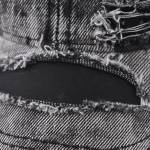 Close-up of vintage washed denim fabric with distressed ripped details and fringe edges