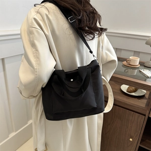 Bolso bandolera grande de nailon negro con correa ancha en un ambiente informal