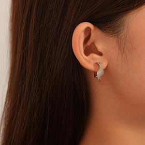 Close-up of twisted silver hoop earrings with textured finish on female ear