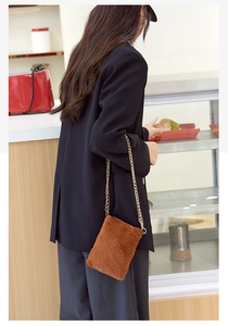 Brown plush crossbody bag with gold chain strap shown on model in cafe setting