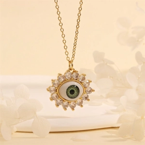 Detail of gold evil eye pendant with green eye center and radiant sunburst cubic zirconia