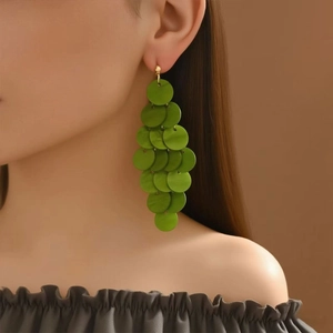 Close-up of grass green multi-layered circular pendant earrings worn by a model