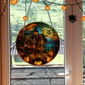 Macro shot of Halloween pumpkin and ghost house stained glass pendant on window