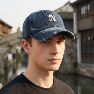 Vintage distressed blue denim baseball cap with white N patch for women in sunset light