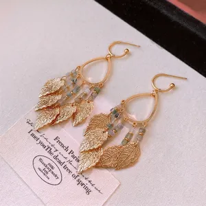 Bohemian gold leaf tassel earrings with multi-color beads on a vintage cream background