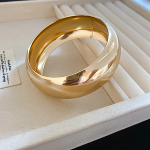 Gros plan du bracelet jonc doré large avec finition polie miroir sur boîte à bijoux