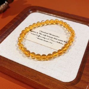 Detail view of round citrine beads on a wooden tray with warm lighting effects