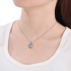 Macro shot of a silver heart pendant necklace with hollow pattern on a female model