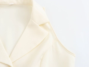 Detailed close-up of beige sleeveless top featuring V-neckline and elegant lapel design